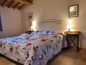 A neatly made bed with floral bedding, two bedside lamps, and a wooden nightstand.