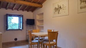 Un coin repas avec une table et des chaises, un téléviseur posé sur un meuble, et des œuvres d’art accrochées au mur.