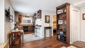 Een moderne keuken met donkerhouten kastjes, een bar en een boekenplank vol diverse spullen.