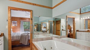 A modern bathroom with a large bathtub, wooden accents, and a glass shower enclosure.