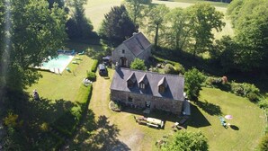 An aerial view of a stone building with a swimming pool, surrounded by lush greenery and trees. - ----Breton hamlet 20 persons---- (LANGOELAN)