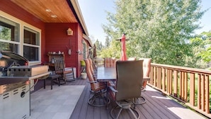 Een terras buiten met een barbecue, een eettafel en stoelen, en een houten omheining.