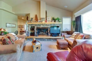 A cozy living room with a stone fireplace, a television, and comfortable seating.