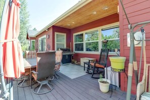 A covered deck with a grill, outdoor seating, and a potted plant.