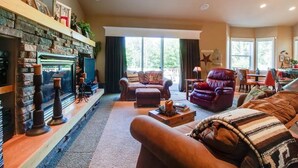 Een gezellige woonkamer met een open haard, leren banken en een groot raam dat natuurlijk licht binnenlaat.