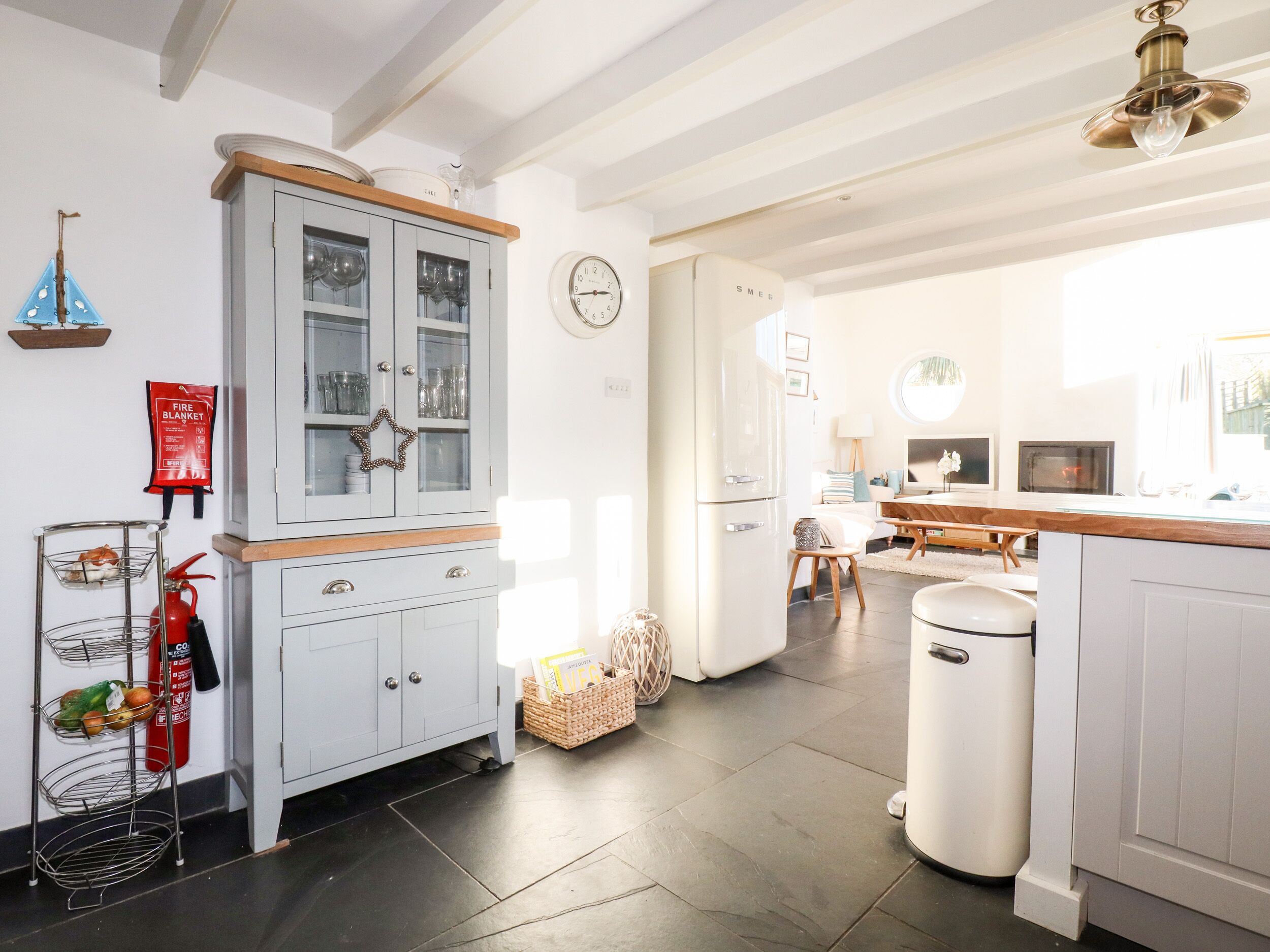 A modern kitchen with a grey cabinet, a fire extinguisher, and a trash bin.