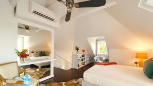 A bedroom with a bed, a desk with a chair, a mirror, a ceiling fan, a window, and a bookshelf. - Charming 1 BR 1.5 BA 19th Century Cottage (Governor's Harbour)