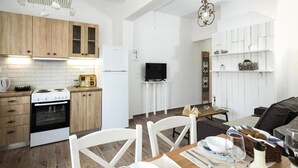 Una cocina moderna con armarios blancos, una estufa y un comedor con una mesa dispuesta para dos.