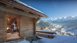 A wooden cabin with a view of a snowy mountain landscape. - Chalet Happyview - luxury holiday for 15 with pool & sauna - OVO Network (Le Grand-Bornand)