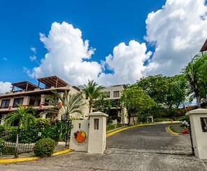 A gated entrance to a residential area with a clear sky and lush greenery.