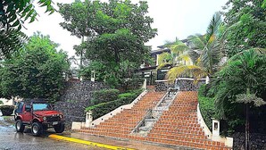 A red SUV parked on a wet road with a brick staircase leading to a building.