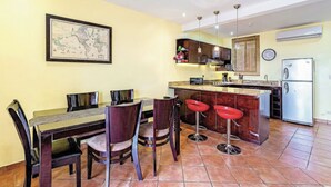 A compact kitchen with a dining area, featuring a map on the wall, a refrigerator, and a bar counter with stools.