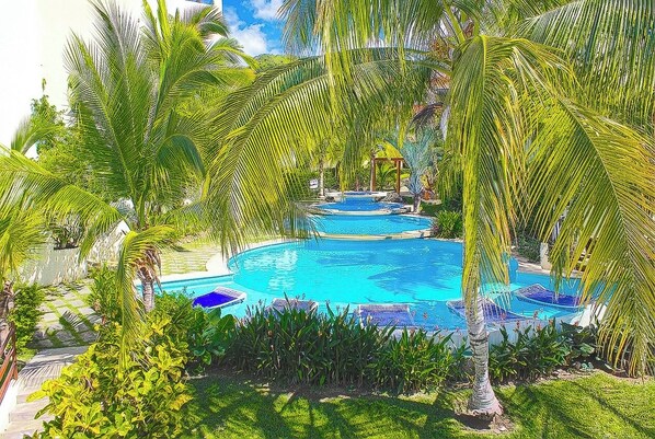 A pool surrounded by palm trees and a gazebo.