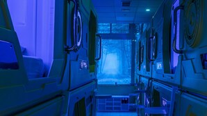 A futuristic room with bunk beds, a digital display showing oxygen levels, and a large window with a view of trees. - Oxygen Hostel (Madrid)