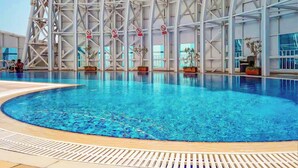 Una gran piscina interior amb un disseny arquitectònic modern, envoltada per un sostre alt i bigues estructurals.