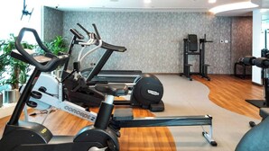 Un gimnàs amb equips de cardio, màquines de peses i una banca.