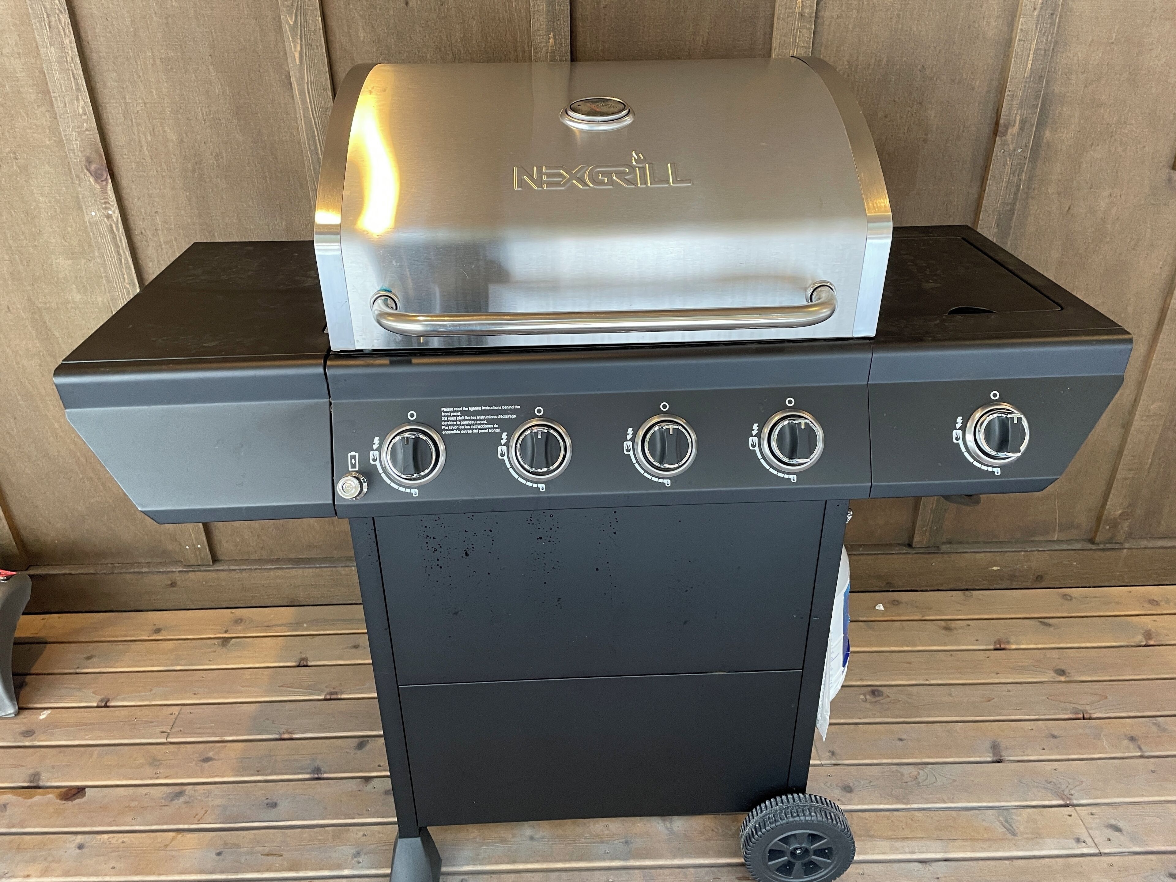 A NEXGRILL barbecue grill with four control knobs and a stainless steel lid.