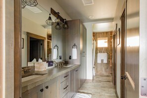 A modern bathroom with a large mirror, two sinks, and a wooden floor.