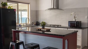 A modern kitchen with a central island, stainless steel appliances, and a view to the outside. - Pet Friendly, 2 Bedroom, Sleeps 4, 250m to Beach, Close to Cafes, Sunshine Coast (Marcoola)