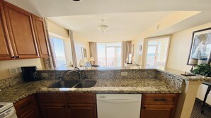 A kitchen with granite countertops, wooden cabinets, a dishwasher, and a coffee maker. - 15th floor 3 bedroom/2 bath condo with million dollar views! (Myrtle Beach)