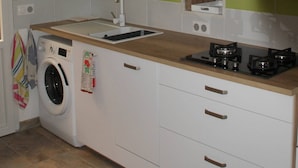 Ett litet kök med tvättmaskin, diskho och spis.