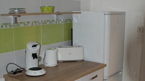 Ett kompakt kök med en bänkskiva i trä, en kaffebryggare, en brödrost och ett kylskåp.