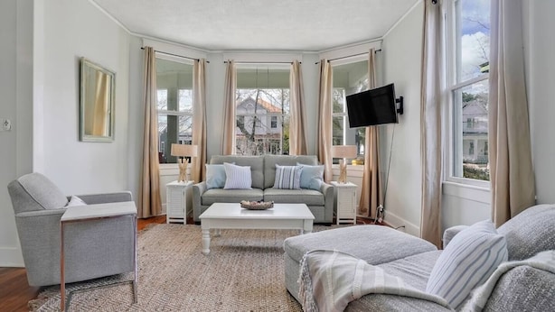 Ein modernes Wohnzimmer mit einem grauen Sofa, einem weißen Couchtisch und einem grauen Sessel.