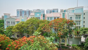Un ensemble immobilier résidentiel comprenant plusieurs immeubles d’appartements, entouré d’une végétation luxuriante et d’arbres en fleurs.