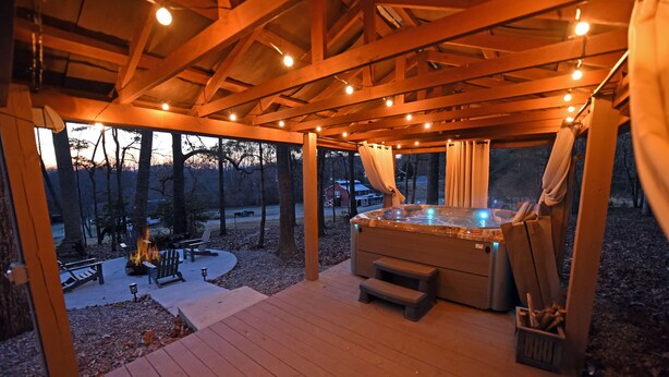 A wooden deck with a hot tub, outdoor seating, and a fire pit.