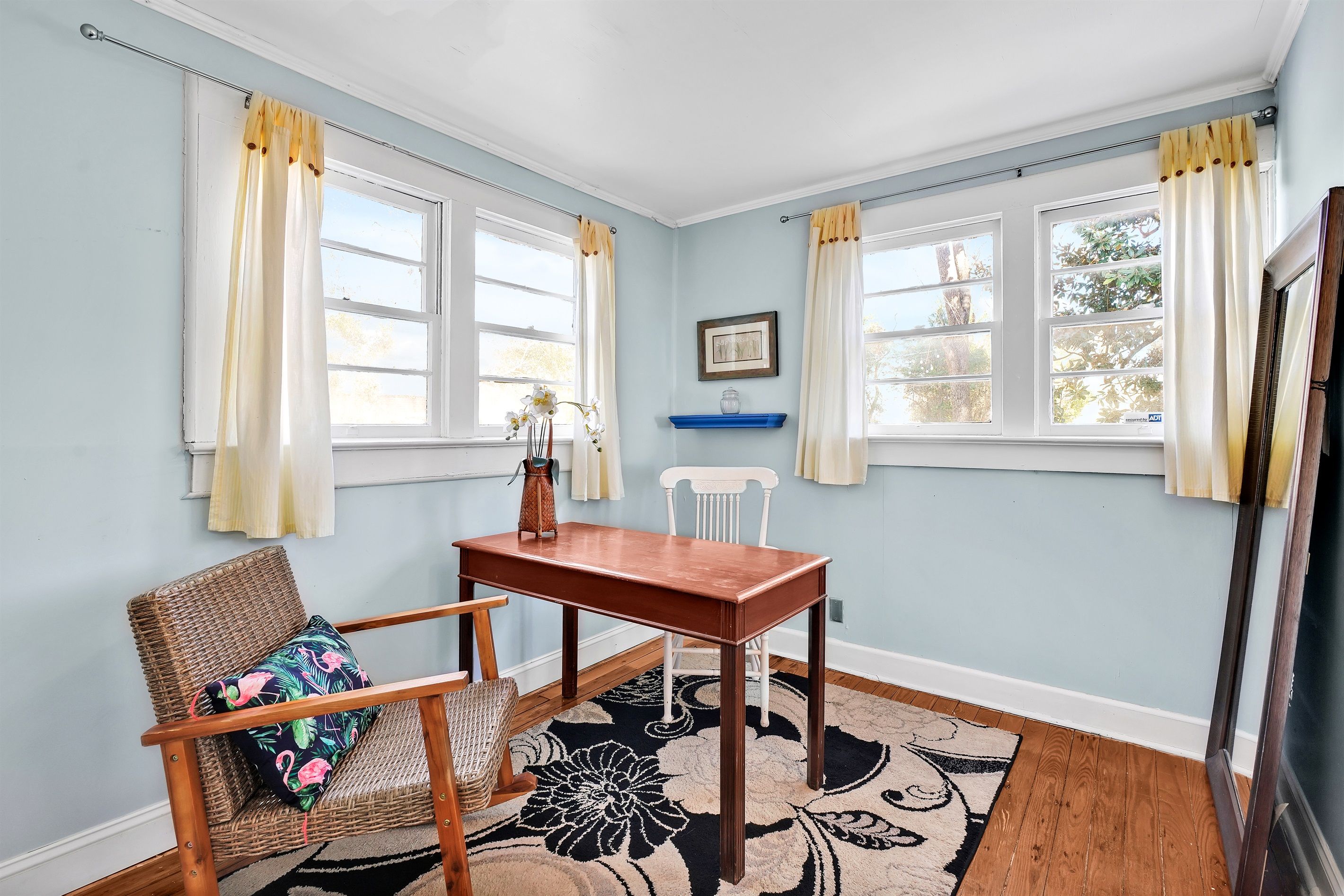 A room with a wooden table, wicker chair, and a patterned rug.