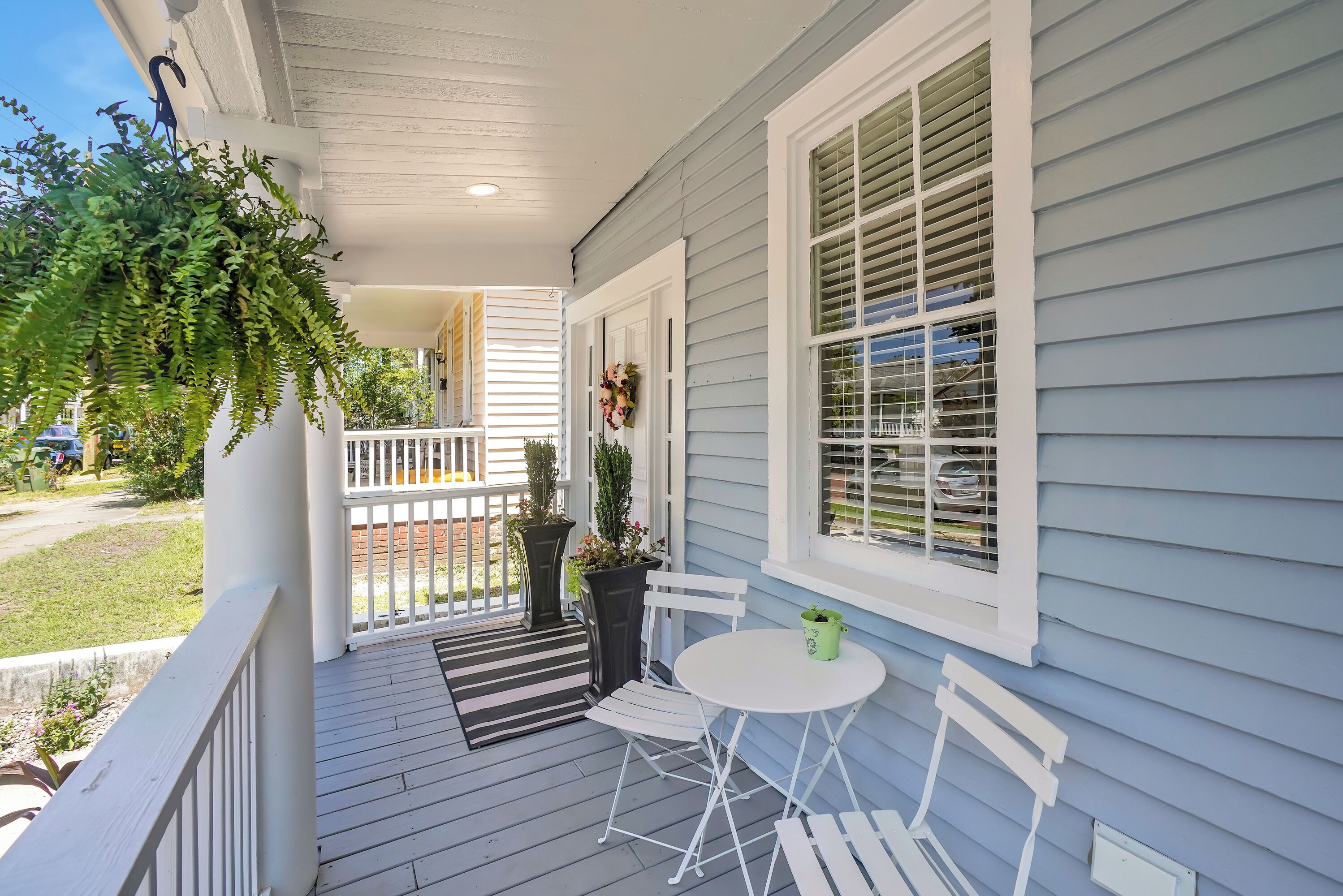 A porch with a white railing, a small table, and two chairs.