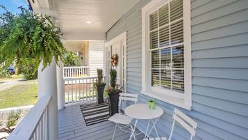 A porch with a white railing, a small table, and two chairs.