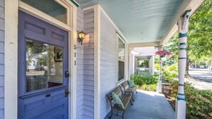 Eine Veranda mit einer blauen Tür, zwei Bänken und einem überdachten Bereich mit Geländer.