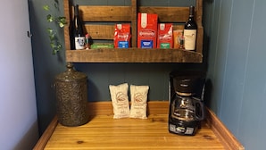 Eine Holztresorecke mit Kaffeemaschine, Weinflaschen und Kaffee-Kapseln.