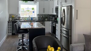 A modern kitchen with white cabinets, stainless steel appliances, and a central island.