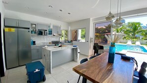 A modern kitchen with a central island, stainless steel appliances, and a view of a swimming pool. - Lazo Beach House, Costa del Sol (San Luis, La herradura)