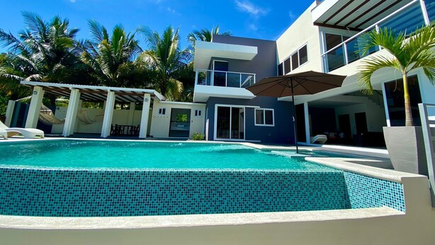 A modern two-story house with a swimming pool, surrounded by palm trees and a clear blue sky. - Lazo Beach House, Costa del Sol (San Luis, La herradura)