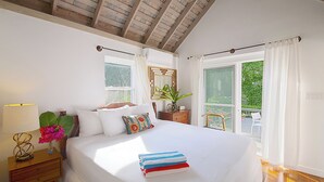 A bedroom with a large bed, a nightstand, a lamp, and a window with curtains.