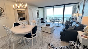 Ein modernes Wohnzimmer mit Essbereich, einer Couch und Blick auf das Meer.
