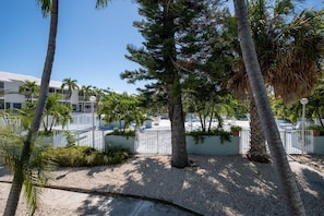Un resort con piscina, palmeras y un edificio blanco con balcones.