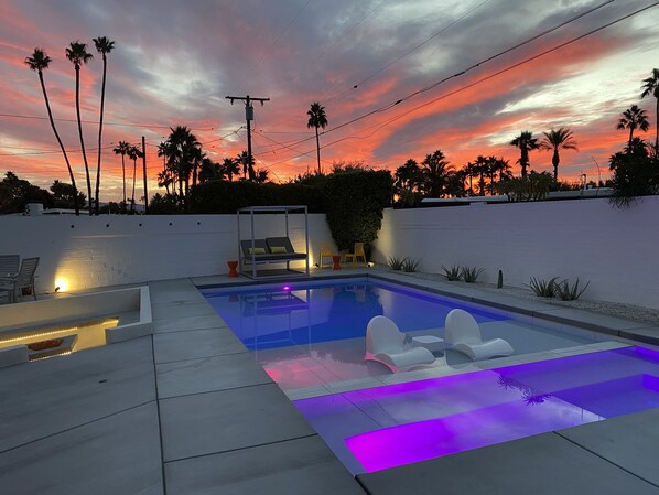 A swimming pool with a modern design, surrounded by a white wall and palm trees. - Luxurious Villa, Renovated, Fully Featured Mid-Century Modern Meiselman Oasis (Palm Springs)
