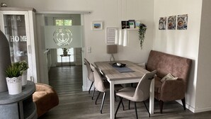 Uma sala de jantar moderna com mesa de madeira, cadeiras acolchoadas e um sofá castanho.