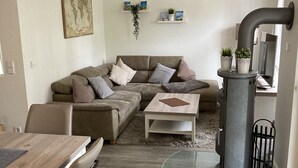 Uma sala de estar moderna com sofá, mesa de centro e mesa de jantar. Há uma lareira e um espelho na parede.