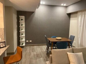 Uma sala de estar moderna com área de jantar, um sofá e uma mesa de centro.