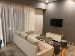Uma sala de estar moderna com um sofá, mesa de centro e uma TV de tela plana na parede.