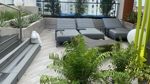 A rooftop terrace with grey lounge chairs, a staircase, and potted plants. - Beautiful apartment in Piantini and spectacular terrace with swimming pool (Santo Domingo)