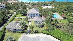 A large house with a pool, surrounded by lush greenery and a view of the ocean. - 1BR Hillside Cottage on Peaceful Private Estate (Governor's Harbour)