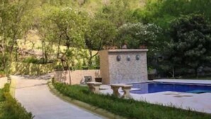 Un sendero conduce a una zona de piscina con una estructura de piedra y vistas a montañas.