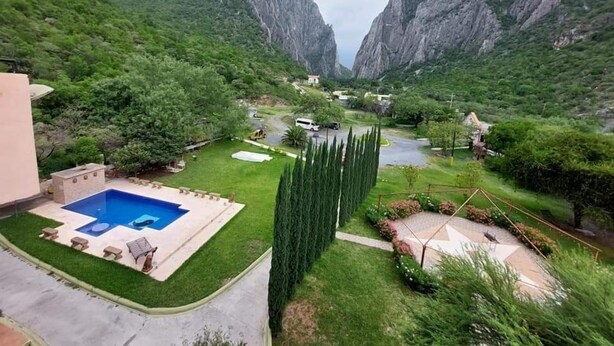 Una zona residencial con piscina, césped cuidado y vista a un valle montañoso.