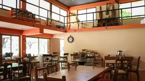 Un comedor amplio con techos altos y ventanas grandes, que cuenta con varias mesas y sillas.